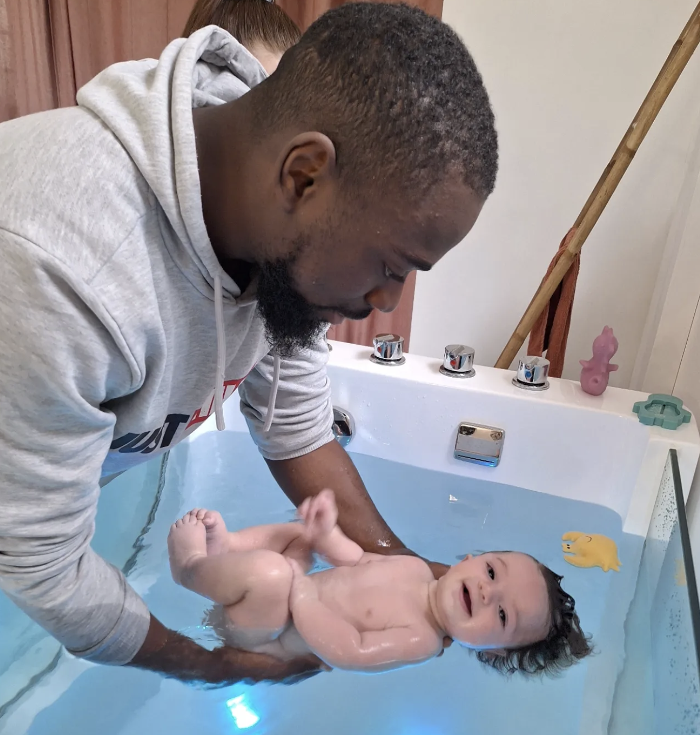 Nouveau-né lors d'un bain enveloppé dans les bras de son parent